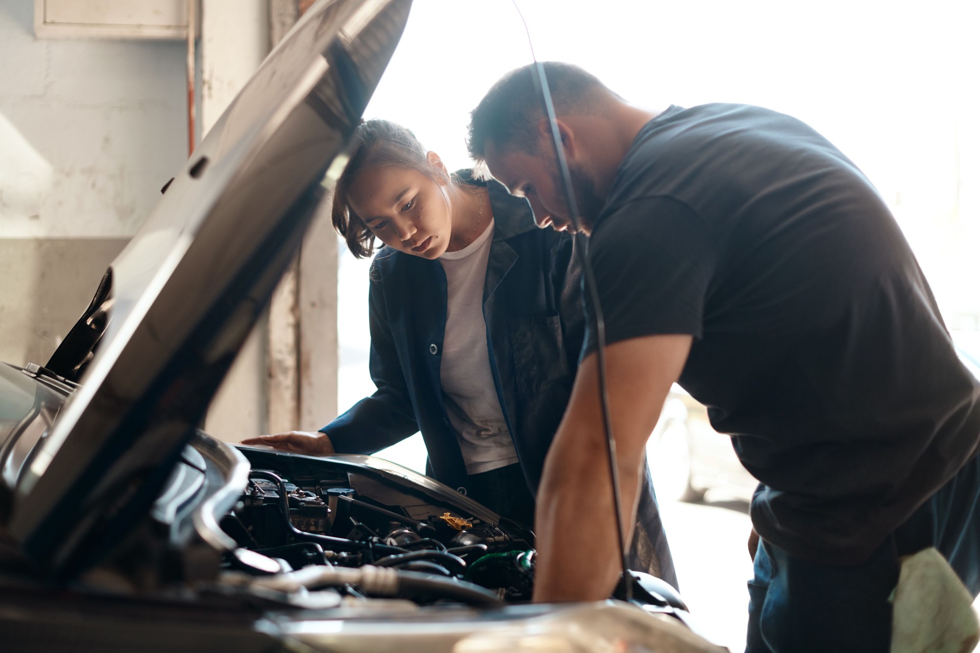 Aufnahme von zwei Mechanikern, die in einer Autowerkstatt gemeinsam an einem Auto arbeiten